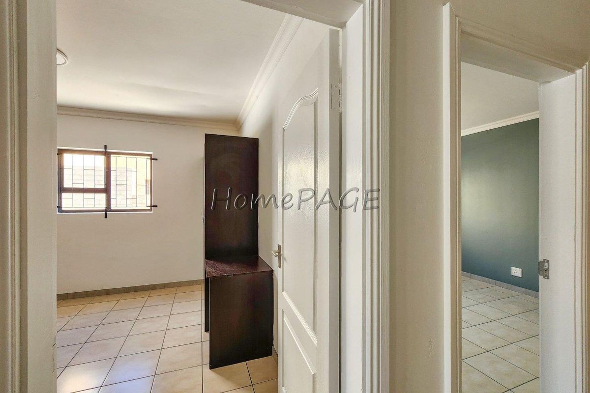A bright, empty bedroom featuring neutral tiled flooring, white walls, and security bars on the window, offering a clean canvas for personalization.