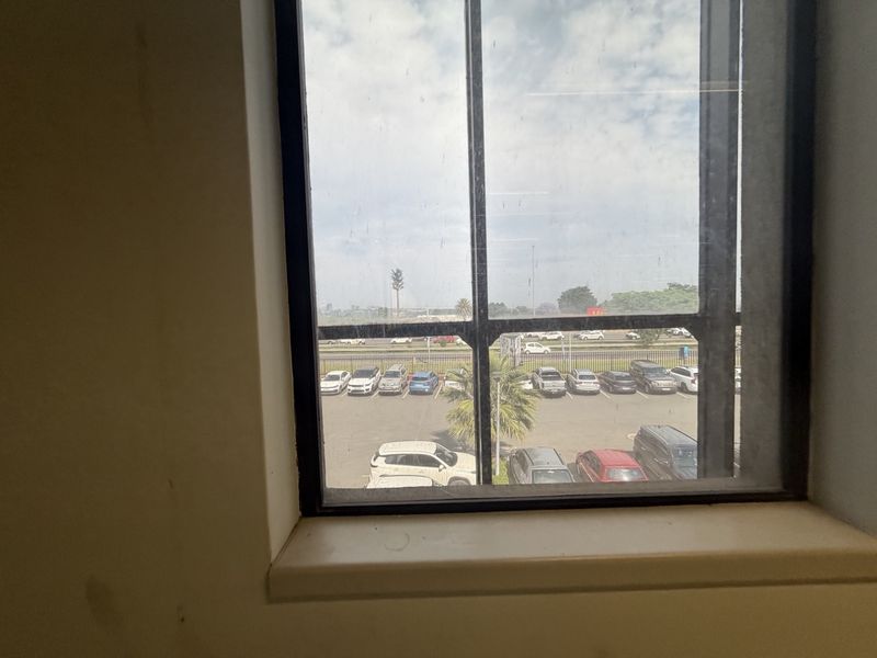 A view from an interior window looking out over a parking area and road.