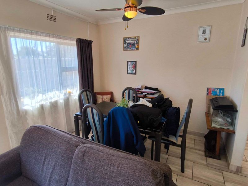 A dining area featuring tiled flooring and a ceiling fan, providing a functional space for meals with natural light from the adjacent window.