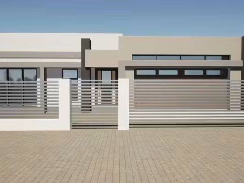 A modern single-story residential facade featuring clean lines, a paved driveway, and contemporary horizontal slat fencing.