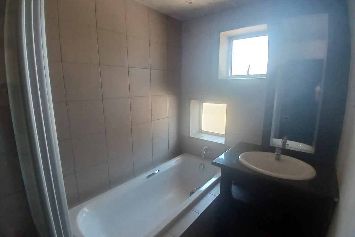 A compact bathroom featuring a built-in bathtub, vanity cabinet with integrated sink, and tiled wall finishes, requiring some ceiling maintenance.