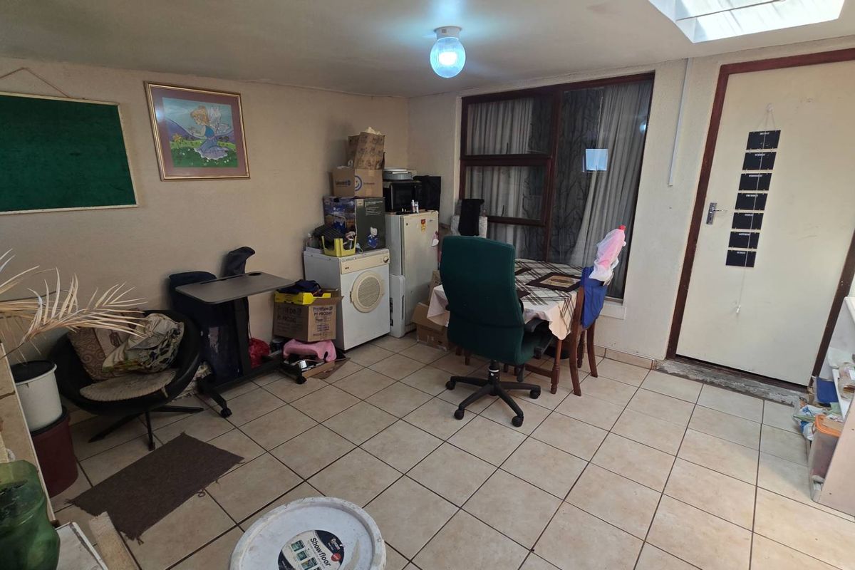 A functional living area featuring tiled flooring, a skylight for natural illumination, and direct access to the exterior.