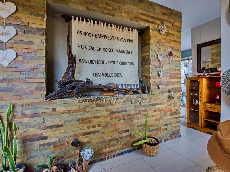 A living room area featuring a prominent stacked stone feature wall with a built-in recessed niche and neutral tiled flooring.
