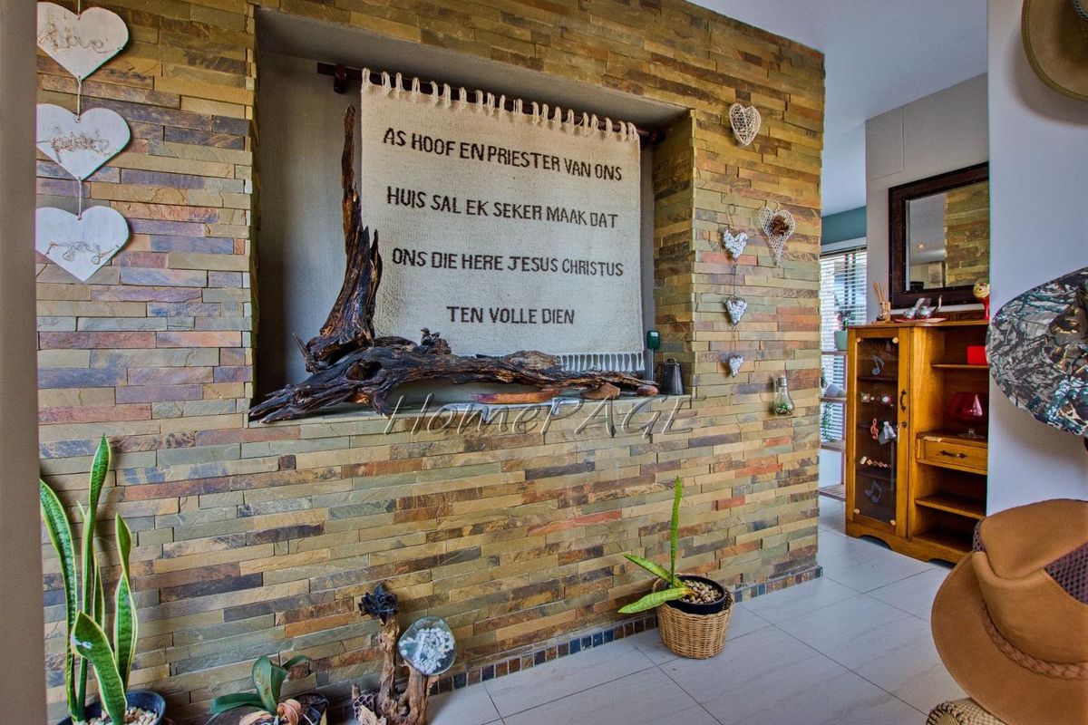 A living room area featuring a prominent stacked stone feature wall with a built-in recessed niche and neutral tiled flooring.