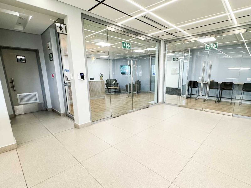 Modern office suite featuring glass-partitioned meeting rooms, high-quality tiled and laminate flooring, and professional recessed grid lighting throughout the workspace.