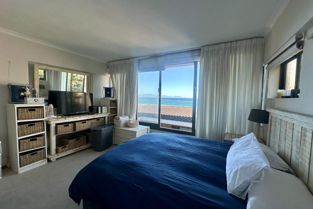 A bedroom featuring carpeted flooring and a large sliding glass door that offers direct views of the ocean.