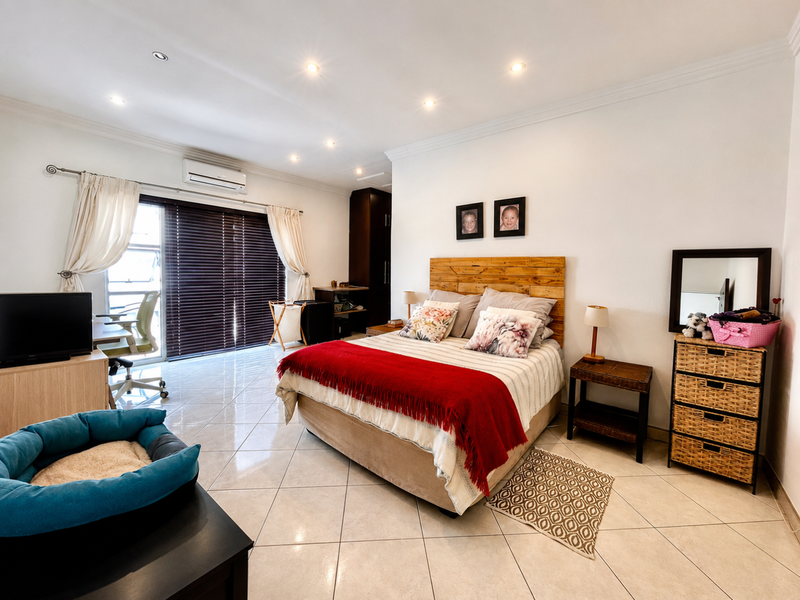 Spacious bedroom featuring tiled flooring, recessed downlighting, a split-system air conditioner, and a sliding glass door providing access to the exterior.