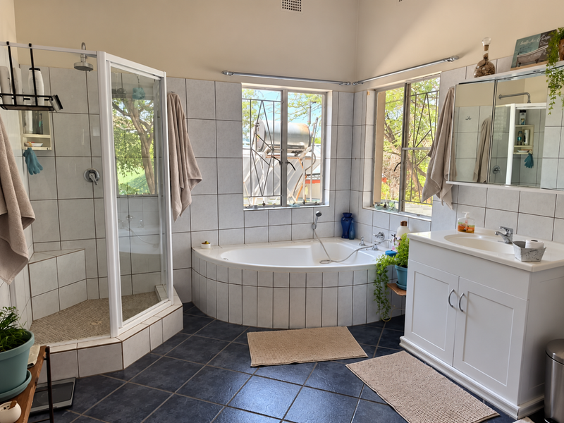 A functional bathroom featuring a corner shower, built-in bathtub, and a white vanity cabinet with integrated sink, finished with tiled walls and dark flooring.