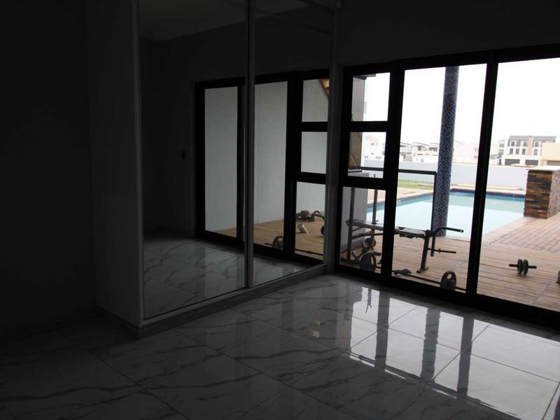 A bright bedroom featuring large sliding glass doors with direct access to a pool deck and a built-in mirrored wardrobe.