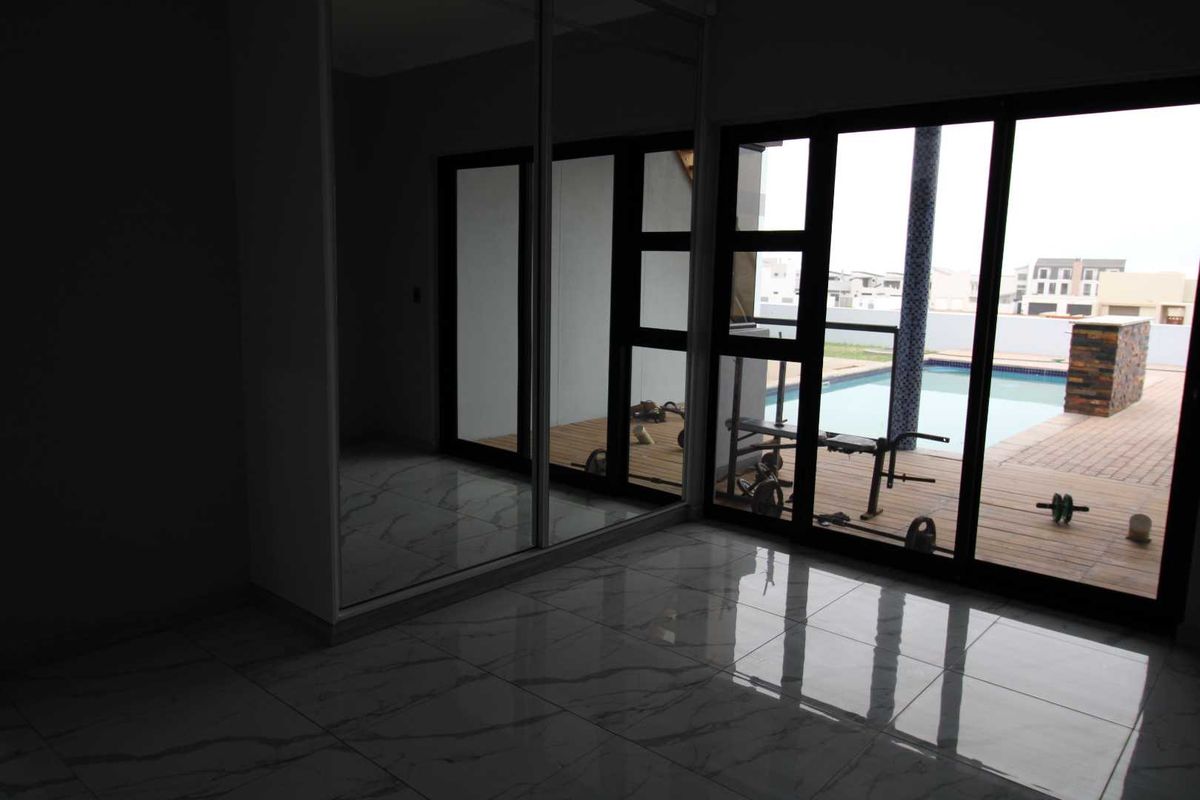 A bright bedroom featuring large sliding glass doors with direct access to a pool deck and a built-in mirrored wardrobe.