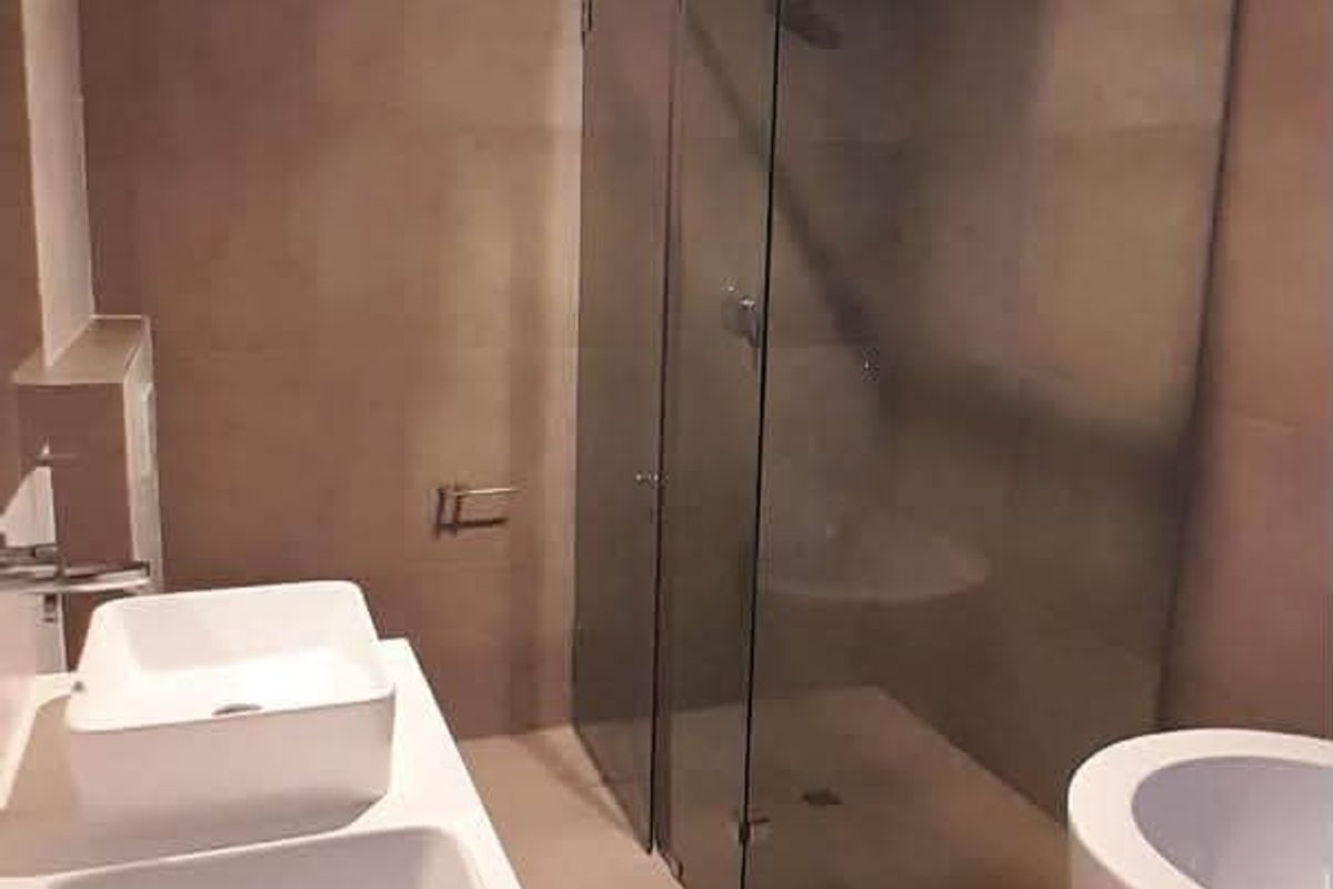 Modern bathroom featuring a double vanity with vessel sinks, a frameless glass shower enclosure, and a sleek freestanding bathtub with neutral wall tiling.