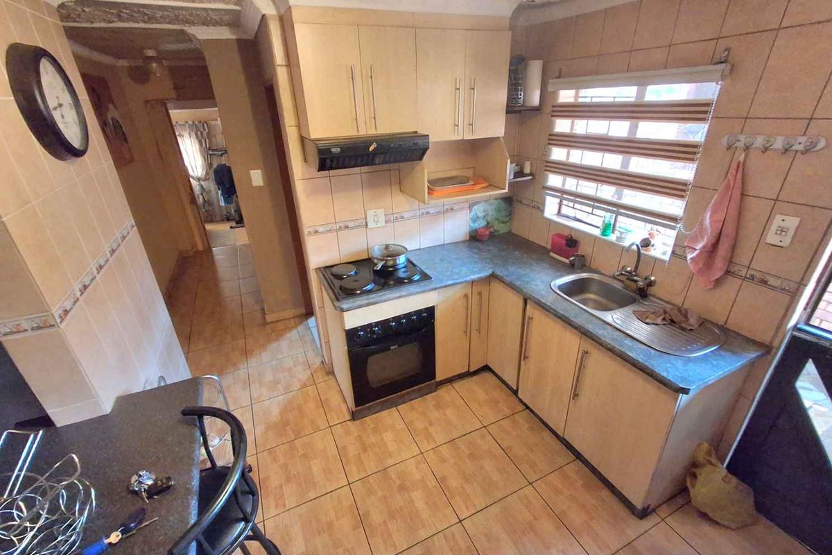 A functional kitchen featuring built-in cabinetry, a fitted oven and hob, tiled splashbacks, and a stainless steel sink with a window view.