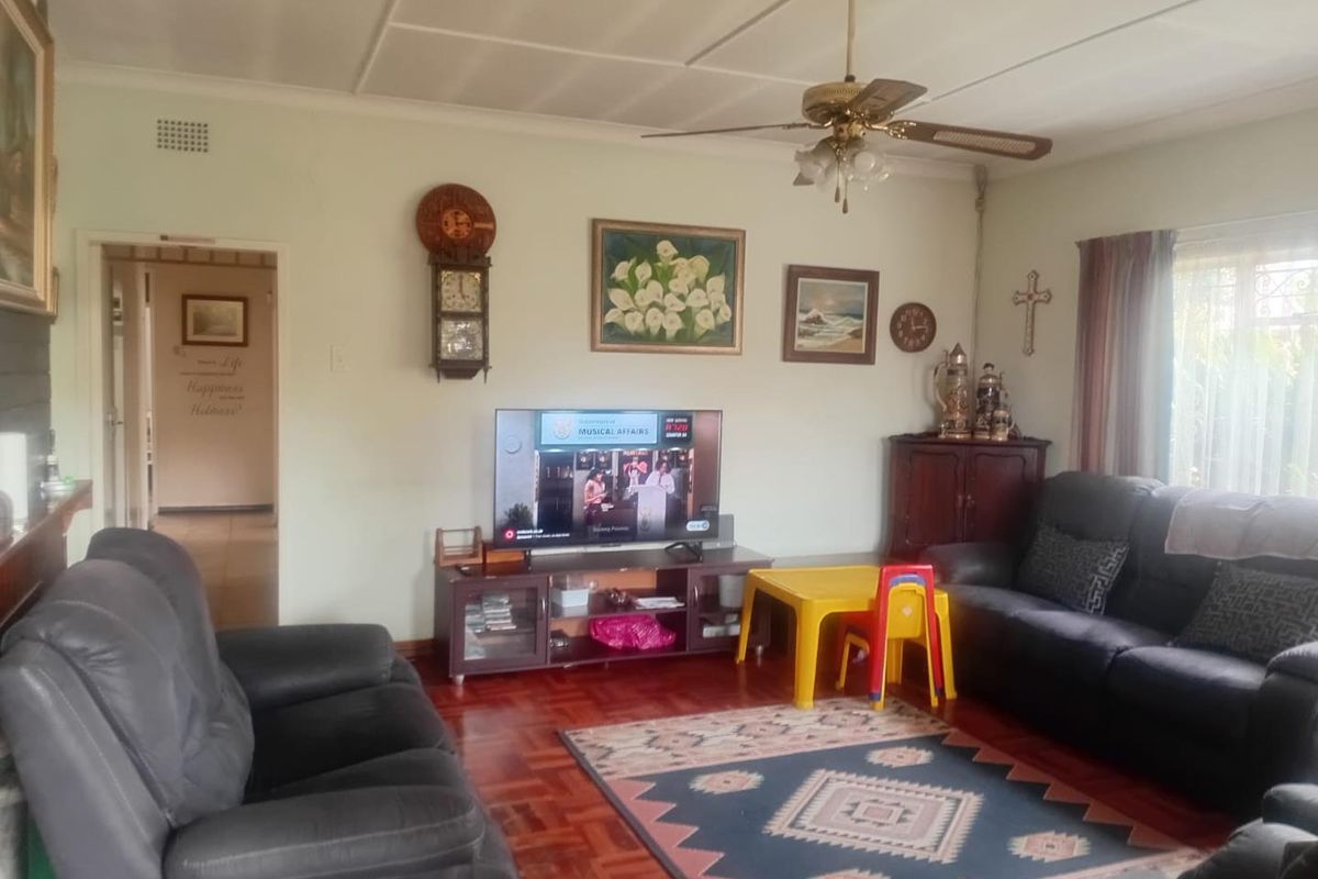 A comfortable living room featuring classic parquet flooring and a ceiling fan, providing a warm and inviting space for family relaxation.