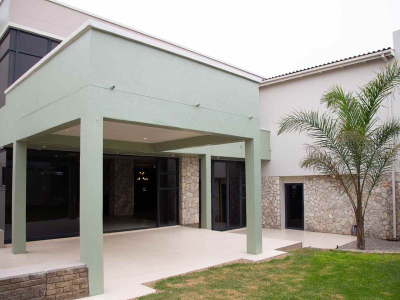 A spacious covered patio featuring stone cladding, modern sliding glass doors, and recessed lighting, providing a seamless transition to the garden area.