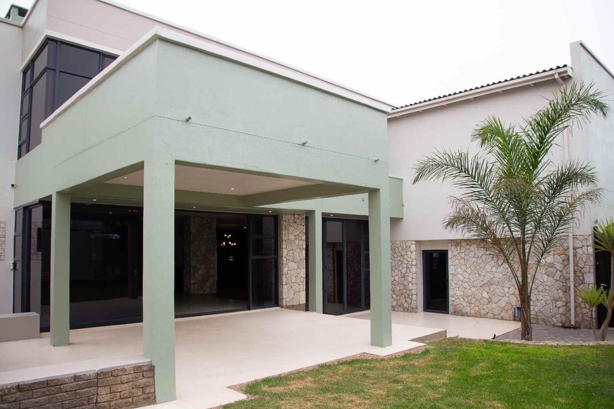 A spacious covered patio featuring stone cladding, modern sliding glass doors, and recessed lighting, providing a seamless transition to the garden area.