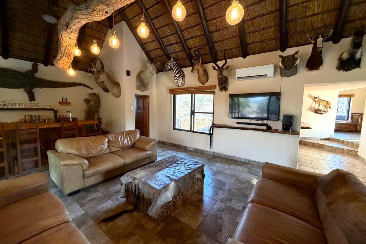 Spacious living area featuring a high thatched ceiling with exposed timber beams, tiled flooring, and a built-in bar area.
