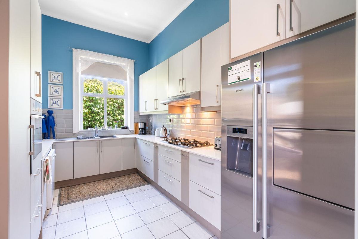 A functional kitchen featuring light-toned cabinetry, subway tile backsplash, gas hob, integrated oven, and tiled flooring, offering a bright and practical workspace.