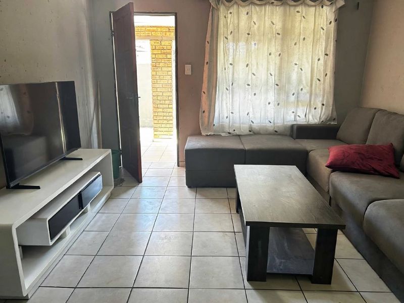 A living room featuring tiled flooring and direct access to an outdoor area, providing a functional space with potential for cosmetic updates.
