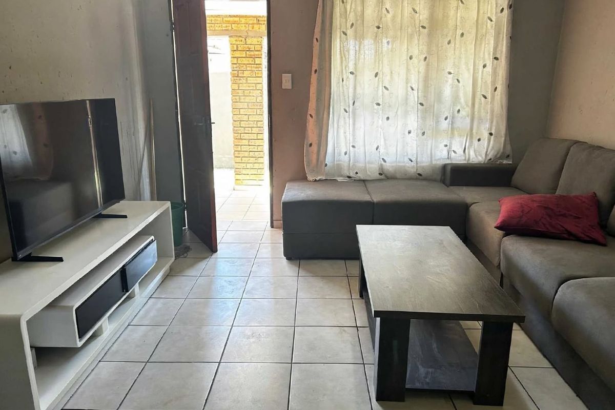 A living room featuring tiled flooring and direct access to an outdoor area, providing a functional space with potential for cosmetic updates.