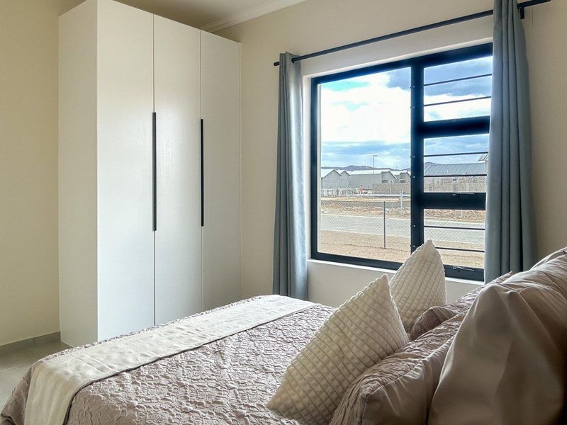 A well-maintained bedroom featuring a modern built-in wardrobe, tiled flooring, and a large window with views of the surrounding area.