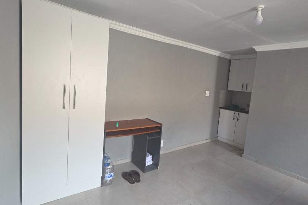 Open plan living area featuring tiled flooring, a built-in wardrobe, and a compact kitchenette with cabinetry.