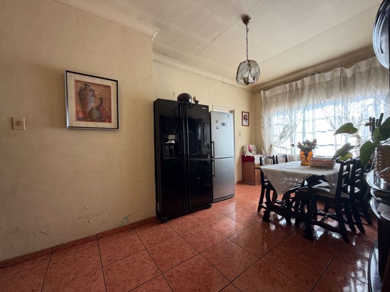 A dining area featuring tiled flooring and a pendant light fixture, requiring cosmetic updates to the walls and ceiling to improve the overall aesthetic.