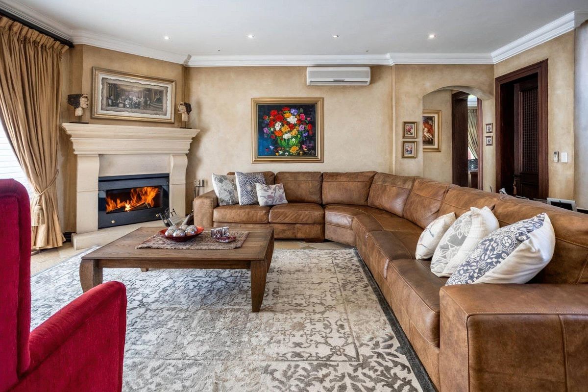 Spacious living room featuring a built-in fireplace with a stone mantel, recessed ceiling lighting, and a wall-mounted air conditioning unit.