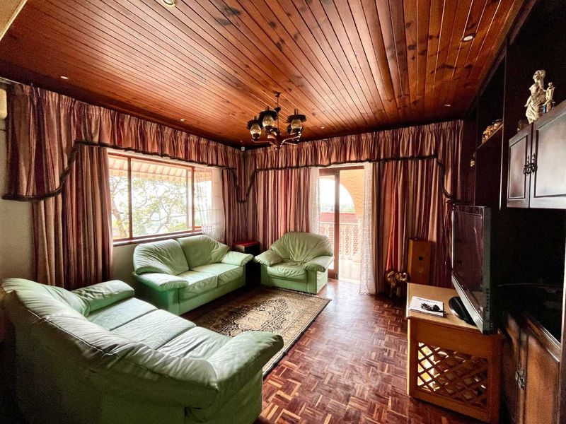 A living room featuring warm timber tongue and groove ceilings, classic parquet flooring, and built-in cabinetry with access to an outdoor area.
