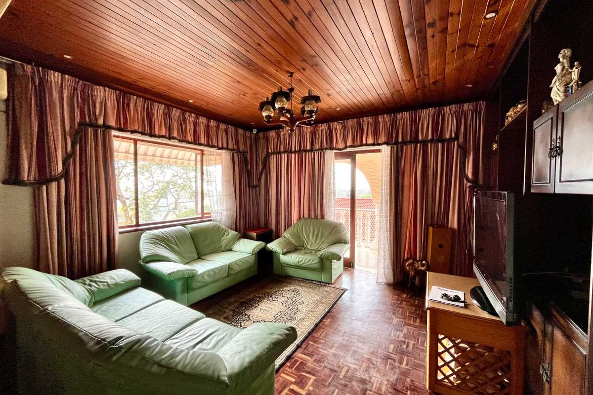 A living room featuring warm timber tongue and groove ceilings, classic parquet flooring, and built-in cabinetry with access to an outdoor area.