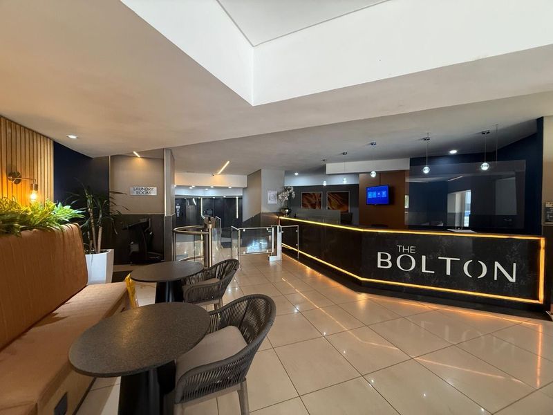 Modern apartment building lobby and reception area featuring polished tile flooring, integrated lighting, and a professional concierge desk.