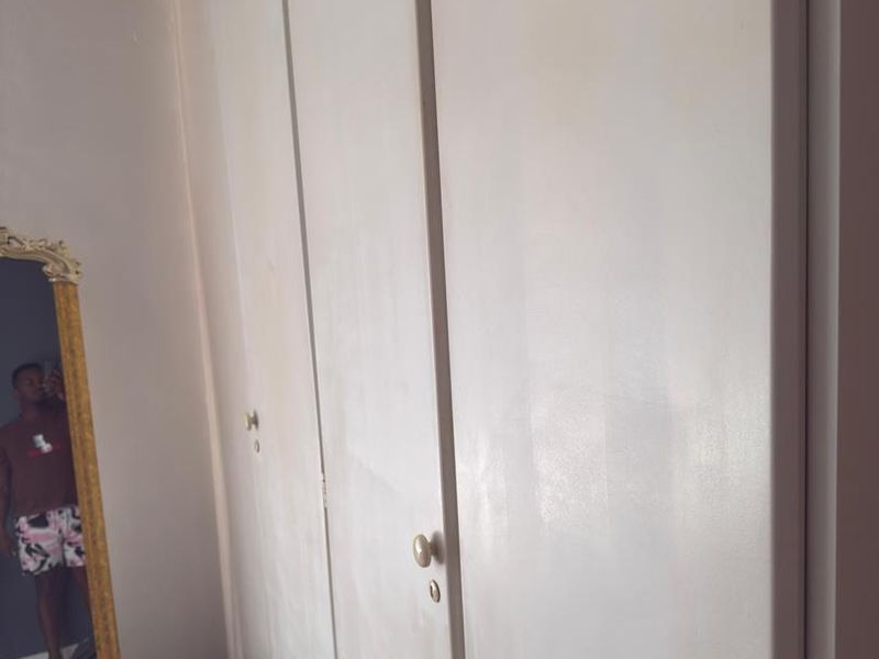 A bedroom featuring floor-to-ceiling built-in cupboards with a plain white finish.