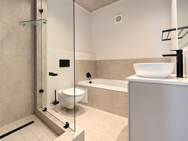 Modern bathroom featuring a walk-in shower with glass screen, built-in bathtub, wall-hung toilet, and a vanity with vessel sink and contemporary black fixtures.