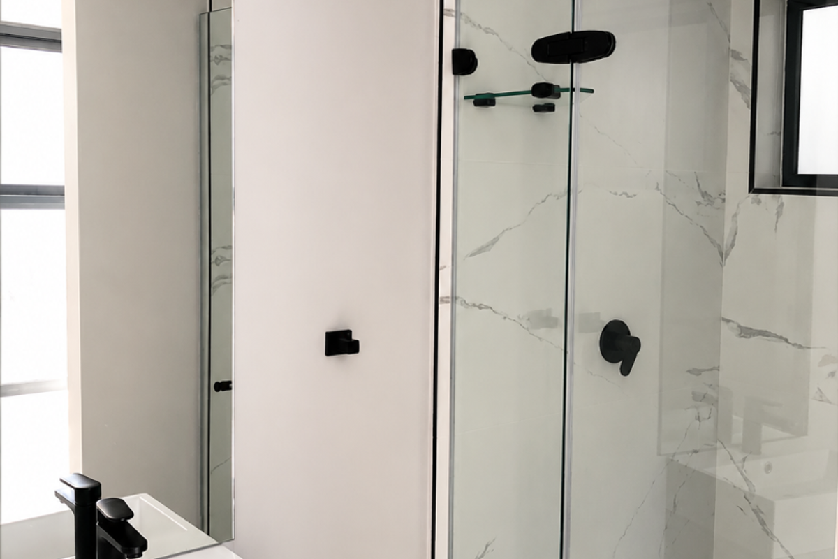 Modern bathroom featuring a sleek vanity with black fixtures, a glass-enclosed shower with marble-look tiling, and contemporary recessed ceiling lighting.