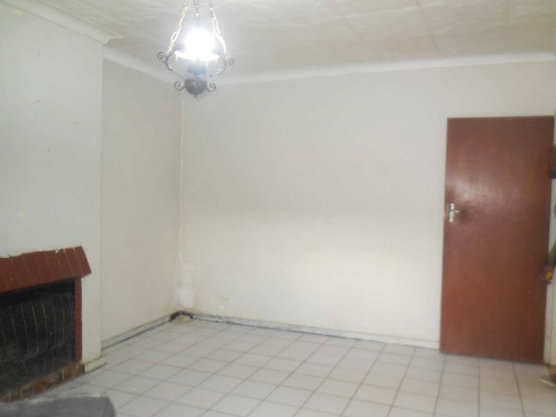 An empty living room featuring tiled flooring, a built-in fireplace, and a coved ceiling, requiring cosmetic updates to improve its overall appeal.