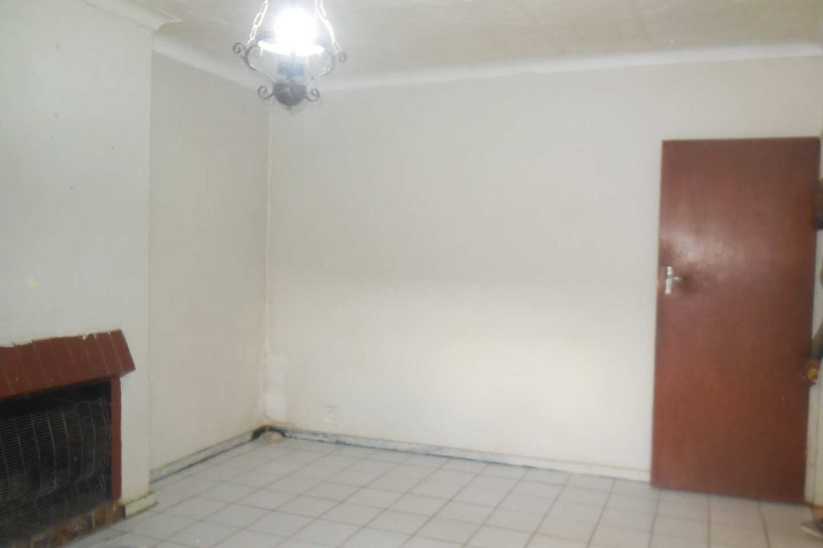 An empty living room featuring tiled flooring, a built-in fireplace, and a coved ceiling, requiring cosmetic updates to improve its overall appeal.