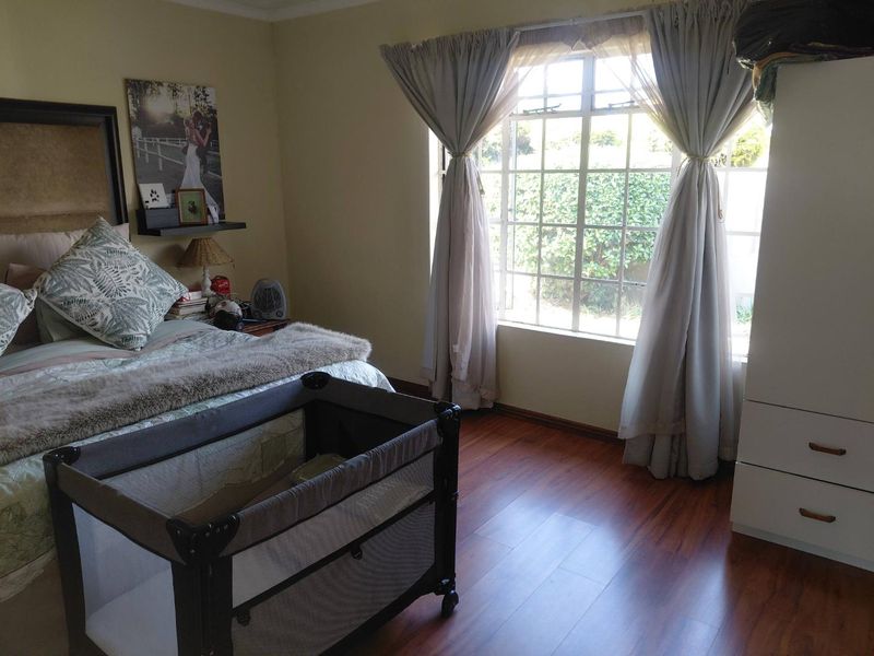 A bedroom featuring laminate flooring and a large grid-pattern window that allows for natural light.