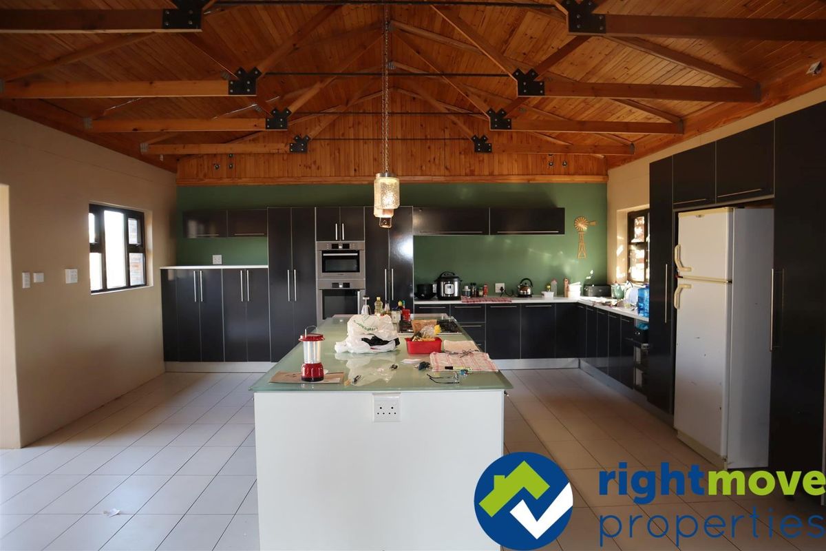 Spacious kitchen featuring dark cabinetry, a central island, and a high vaulted timber ceiling with exposed trusses.