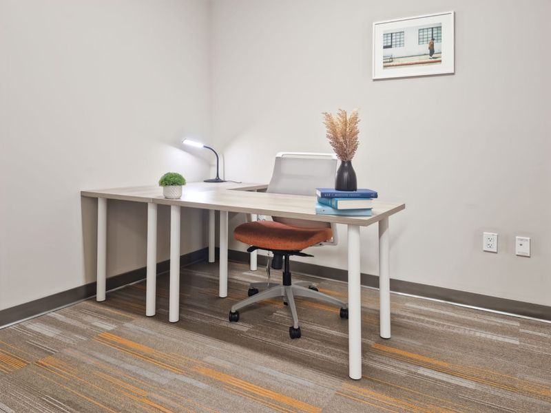A clean and functional office space featuring neutral wall finishes, carpeted flooring, and integrated electrical and data connectivity points.