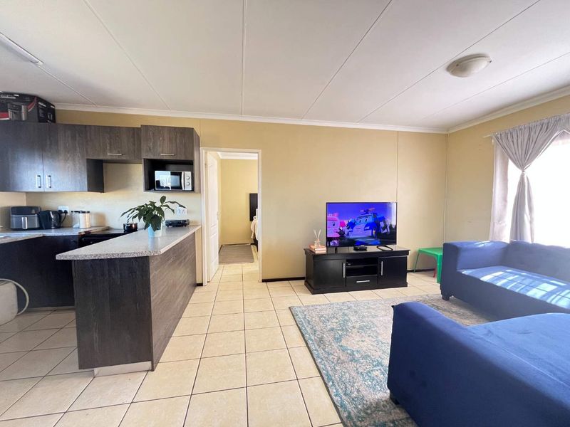 Open-plan living area featuring a kitchen with dark cabinetry and tiled flooring, seamlessly flowing into the lounge space.