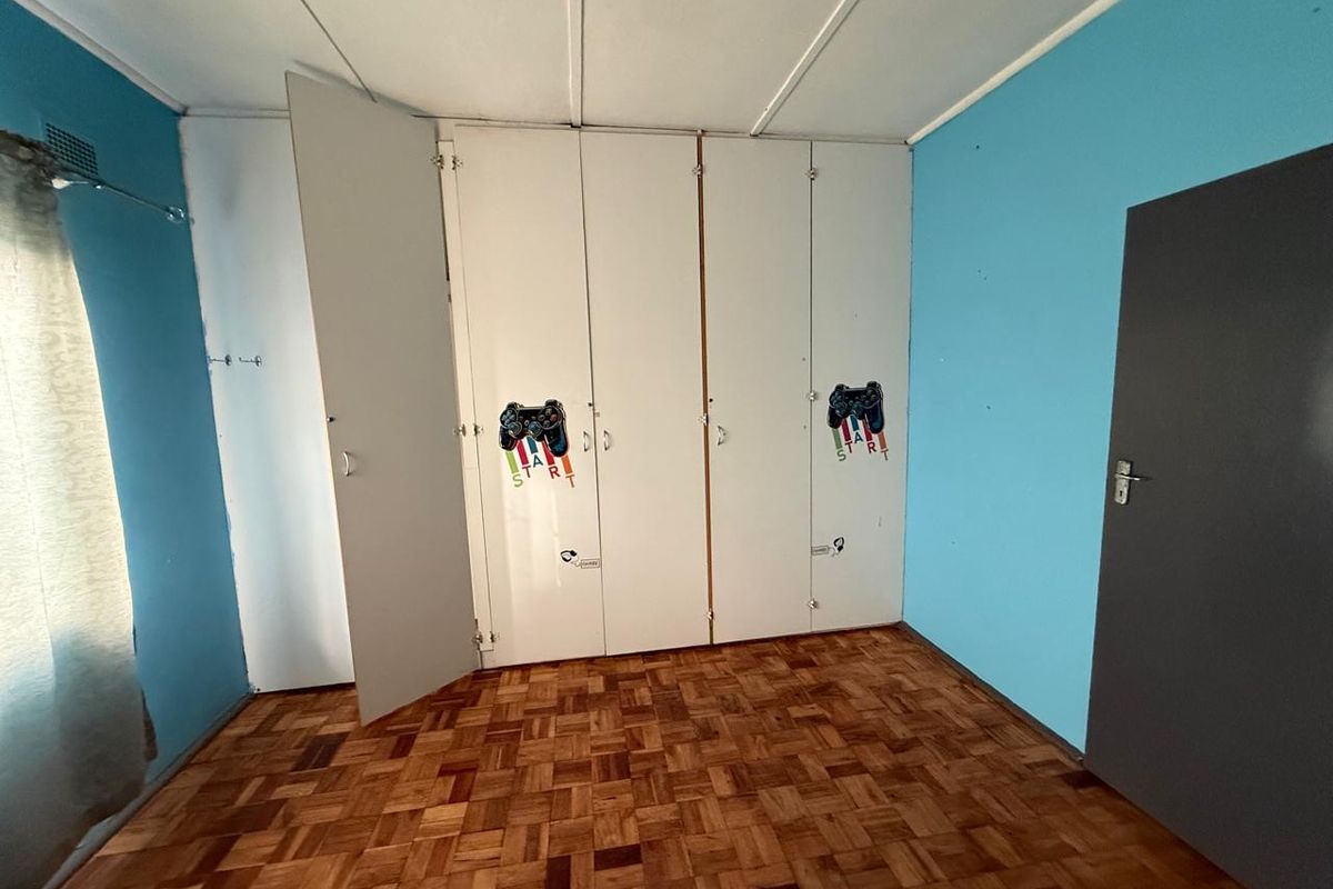 A bedroom featuring classic parquet flooring, built-in floor-to-ceiling wardrobes, and blue accent walls.