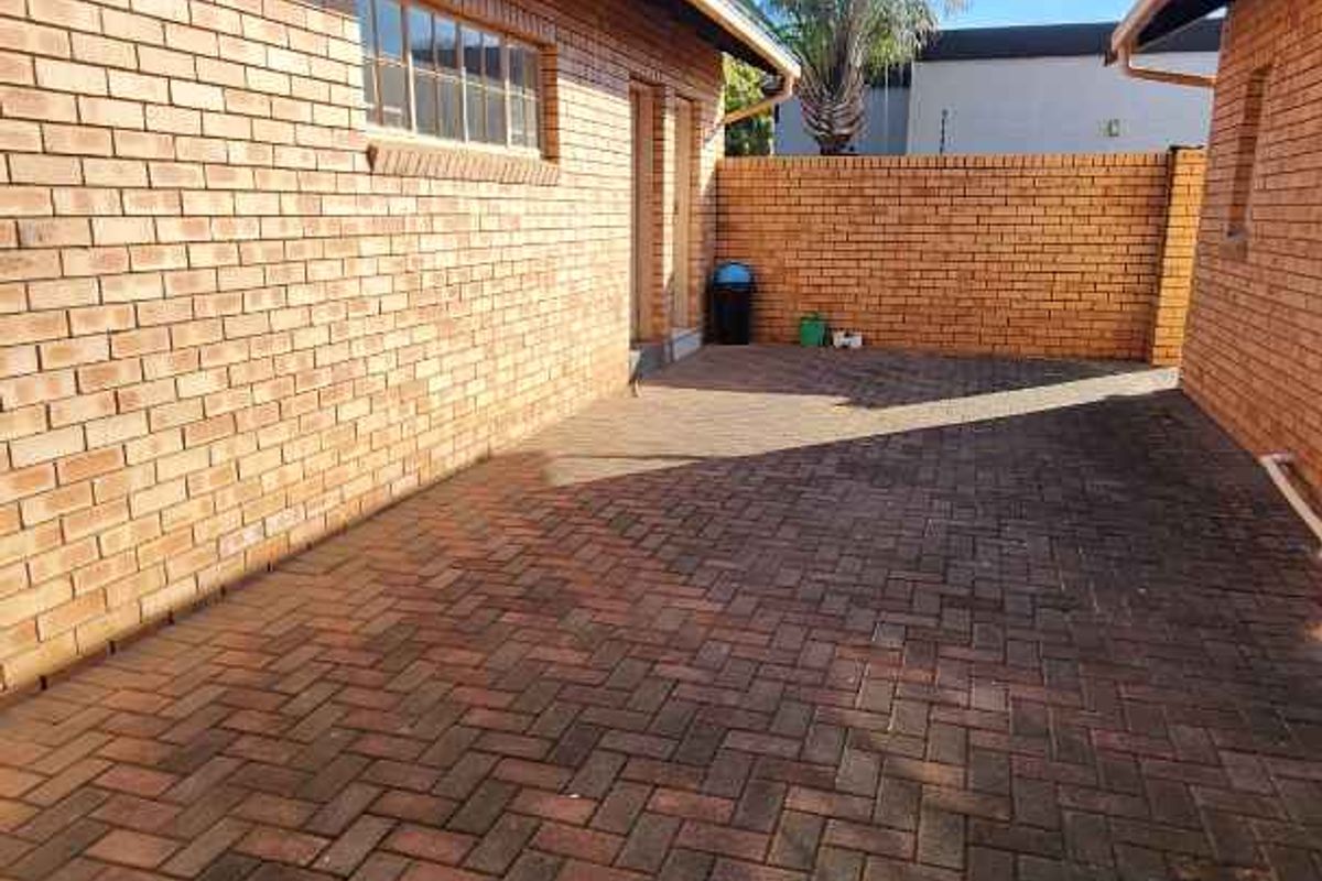 A paved side courtyard area featuring face-brick walls and a secure perimeter boundary, providing a functional outdoor utility space.