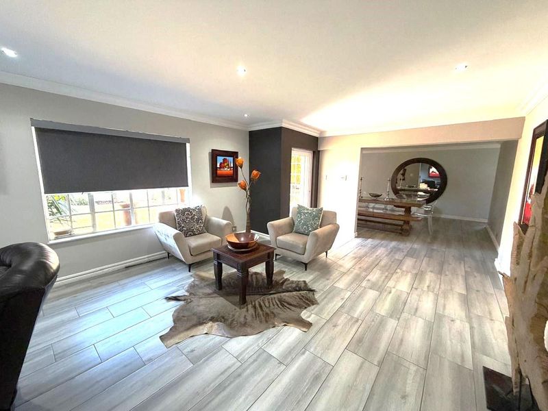 Spacious open-plan living and dining area featuring modern wood-look tile flooring, recessed lighting, and neutral wall finishes.
