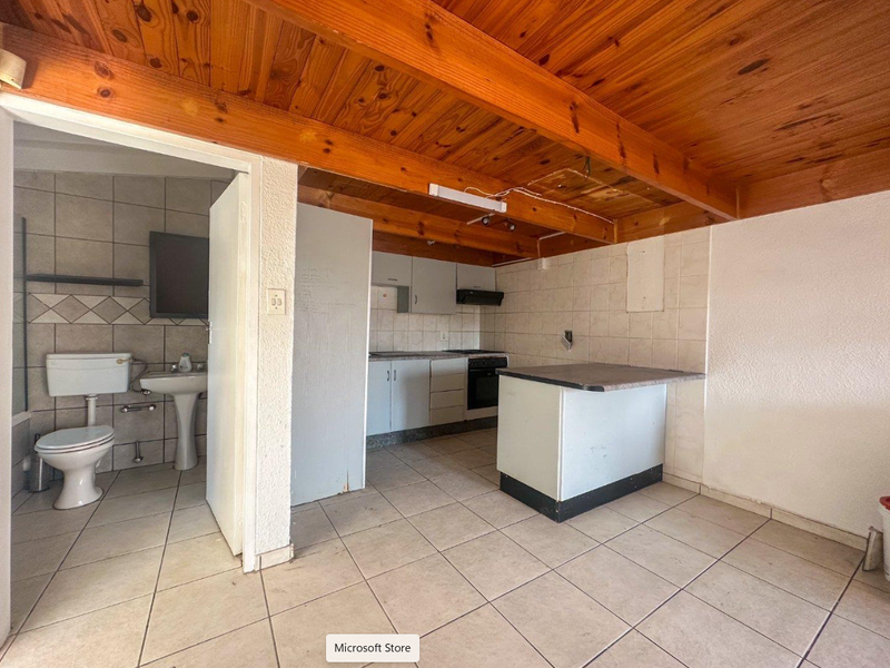 Open plan kitchen and bathroom area featuring exposed timber ceiling beams, tiled flooring, and functional built-in cabinetry, offering potential for modern renovation.
