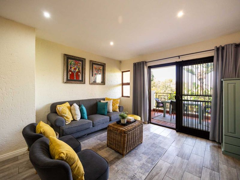 A bright living room featuring tiled flooring, recessed downlights, and a sliding glass door providing direct access to an outdoor balcony area.