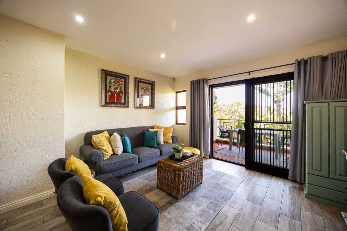 A bright living room featuring tiled flooring, recessed downlights, and a sliding glass door providing direct access to an outdoor balcony area.