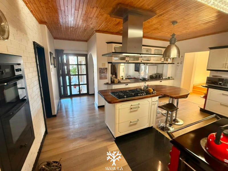 Spacious kitchen featuring a central island with a gas hob, timber ceiling, and built-in oven, offering a blend of rustic and modern finishes.