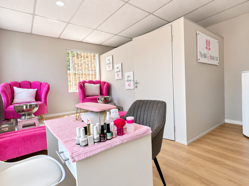 A well-maintained commercial beauty salon space featuring laminate flooring, a suspended ceiling, and secure window treatments.