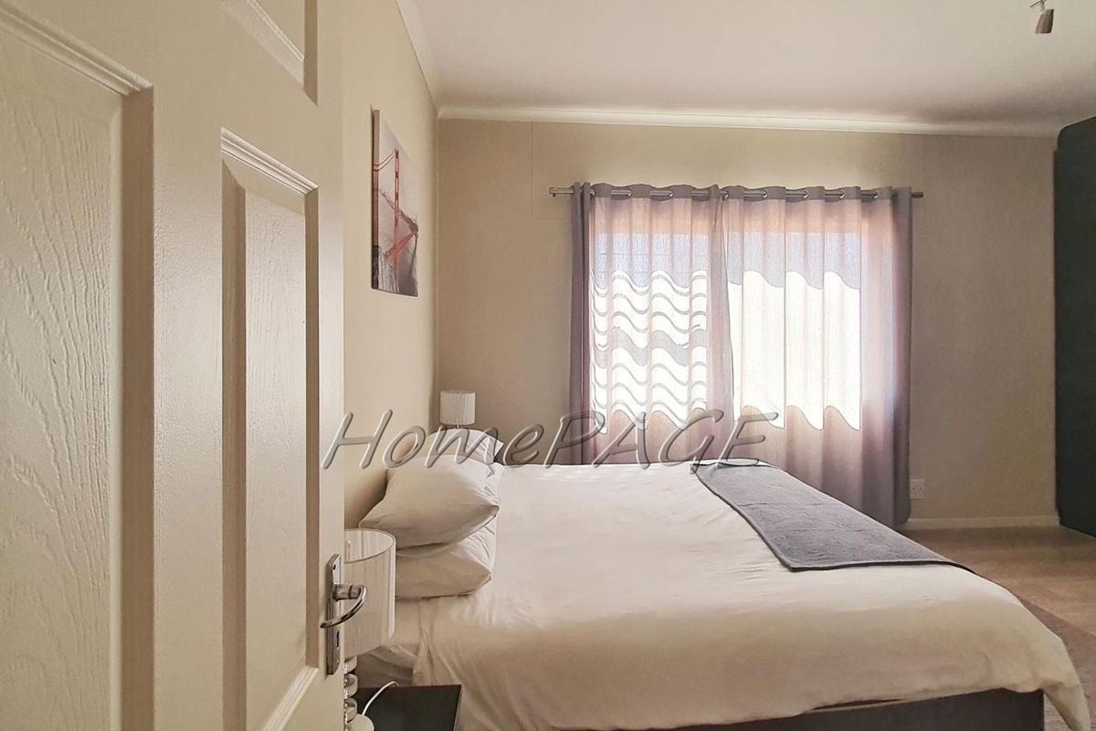 A well-lit bedroom featuring built-in floor-to-ceiling wardrobes and neutral wall finishes.