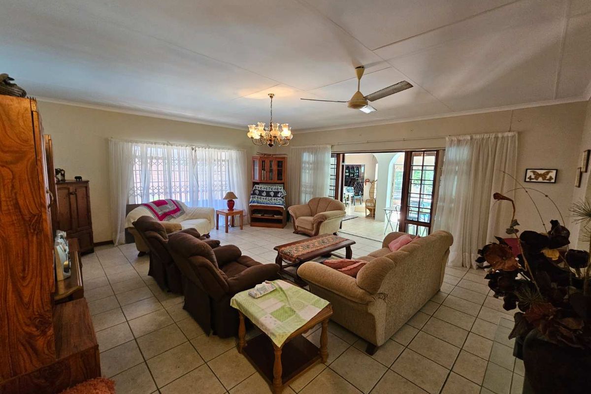 Spacious living room featuring tiled flooring, a ceiling fan, and large sliding doors providing seamless access to the outdoor patio area.