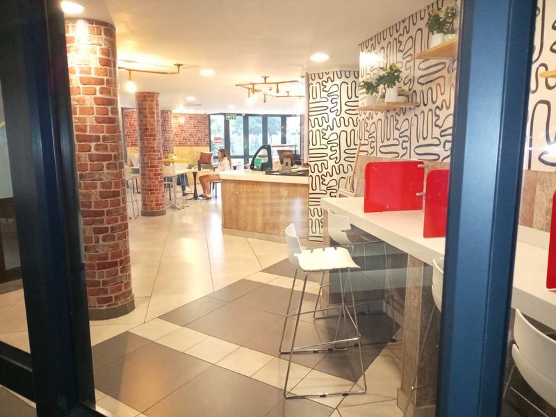 A modern clubhouse interior featuring exposed brick columns, tiled flooring, and a built-in service counter with contemporary lighting and decorative wall finishes.